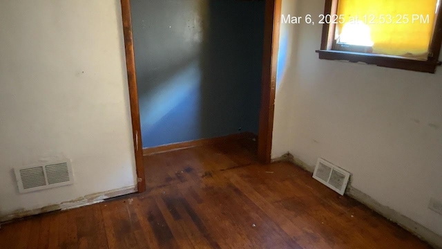 hallway featuring visible vents, baseboards, and wood finished floors