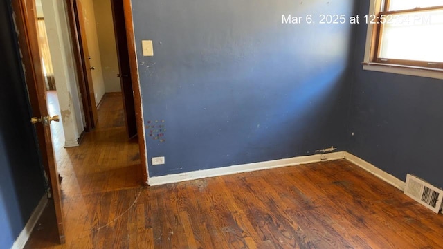 empty room featuring wood finished floors, visible vents, and baseboards