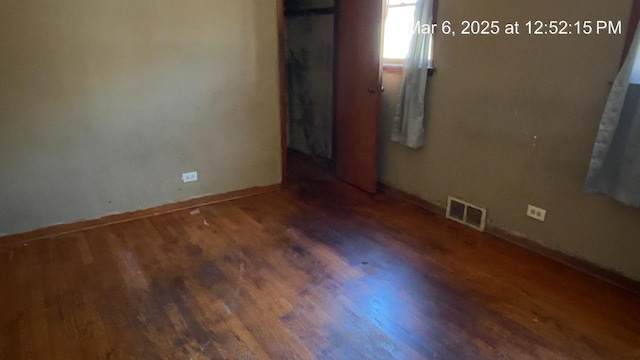 empty room featuring visible vents, baseboards, and wood finished floors