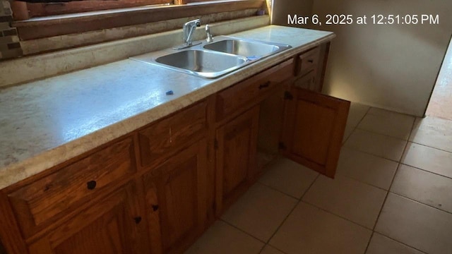 kitchen featuring light tile patterned floors, brown cabinets, light countertops, and a sink