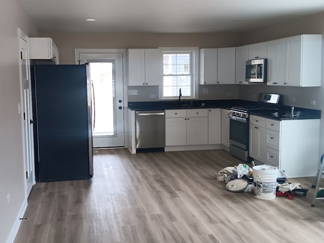 kitchen featuring appliances with stainless steel finishes, sink, white cabinets, and light hardwood / wood-style flooring