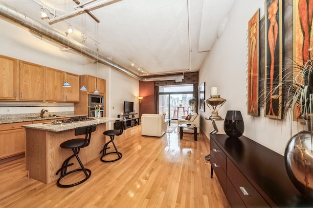 kitchen featuring a breakfast bar area, appliances with stainless steel finishes, track lighting, light hardwood / wood-style floors, and a kitchen island