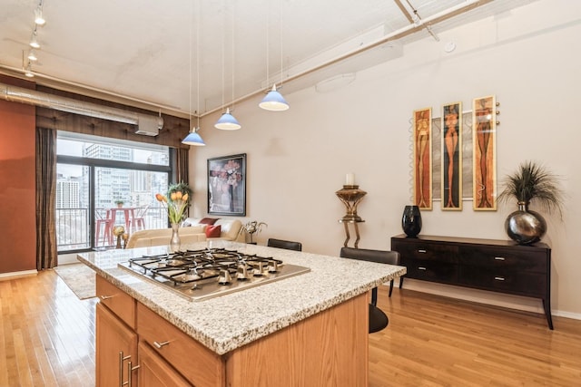 kitchen with stainless steel gas stovetop, a center island, hanging light fixtures, and light wood-type flooring