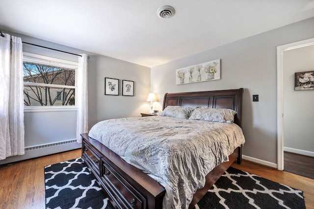 bedroom with a baseboard radiator and hardwood / wood-style floors