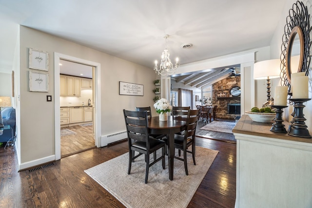 dining area featuring sink, a baseboard heating unit, vaulted ceiling with beams, dark hardwood / wood-style flooring, and a stone fireplace