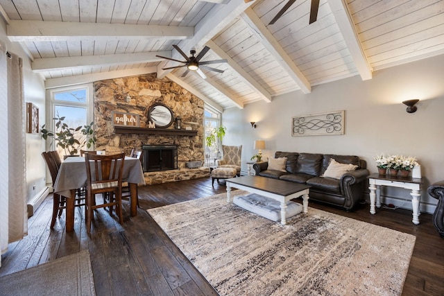 living room featuring a stone fireplace, high vaulted ceiling, dark hardwood / wood-style flooring, beamed ceiling, and ceiling fan