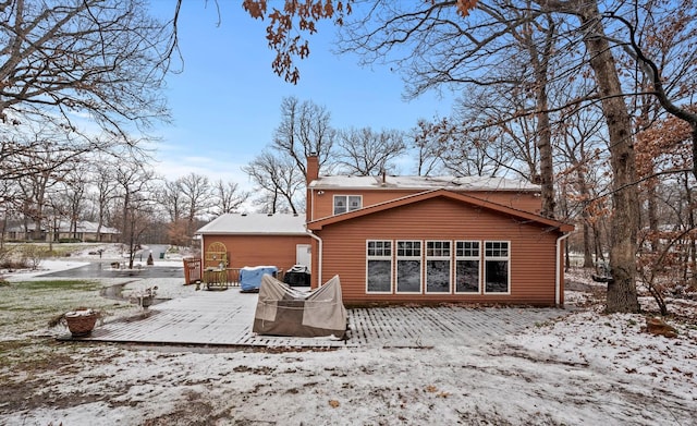 snow covered back of property with a deck