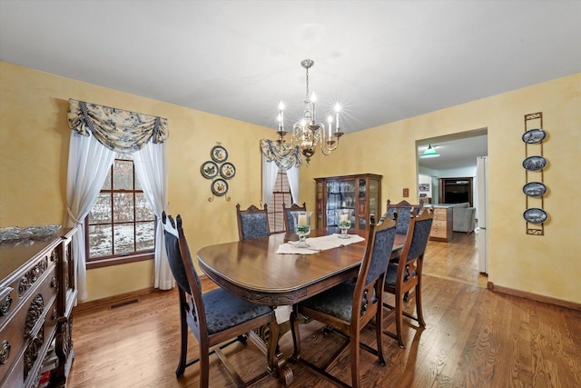 dining space featuring hardwood / wood-style flooring and an inviting chandelier