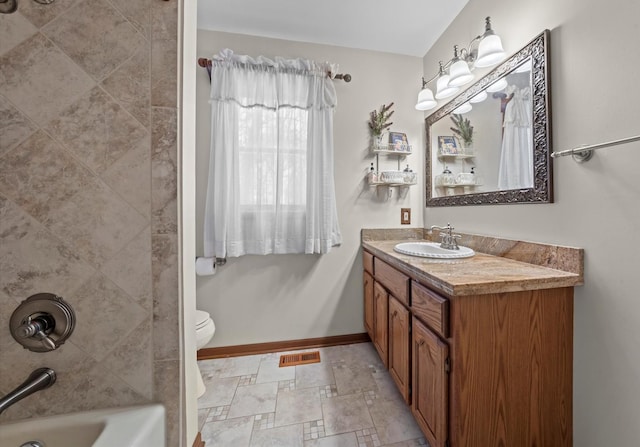 full bathroom featuring tiled shower / bath combo, vanity, and toilet