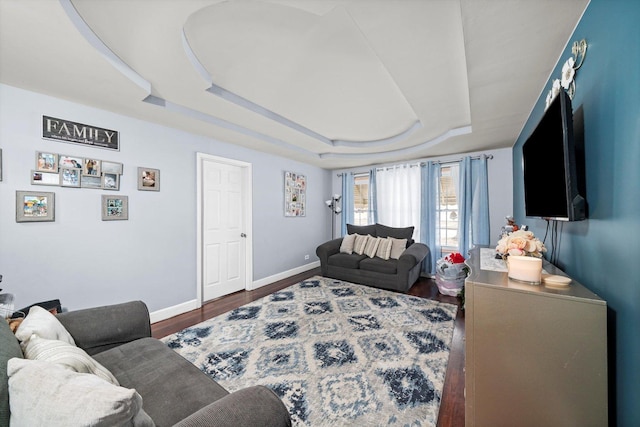 living room with a tray ceiling and dark hardwood / wood-style floors