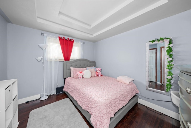 bedroom featuring dark hardwood / wood-style flooring and a tray ceiling