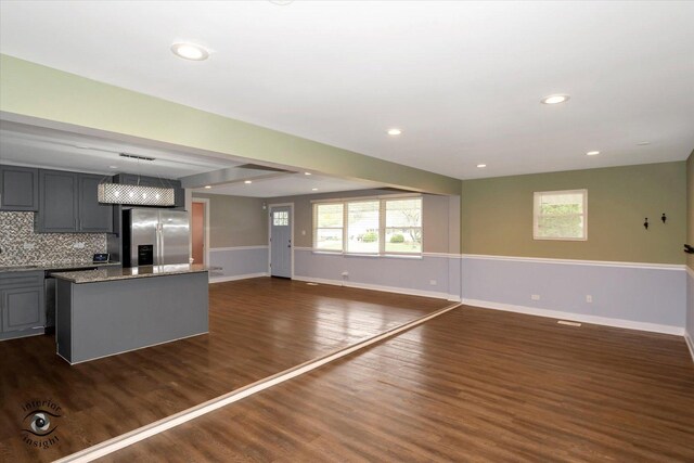 kitchen with stainless steel fridge with ice dispenser, dark wood-type flooring, gray cabinets, and a center island