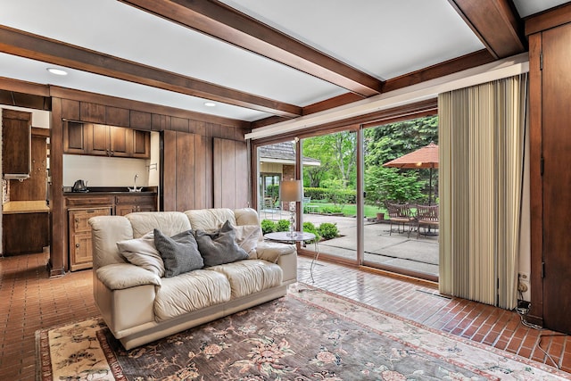 living room featuring beamed ceiling and wooden walls