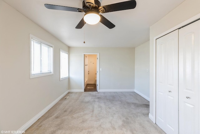 unfurnished bedroom featuring ceiling fan, connected bathroom, light carpet, and a closet