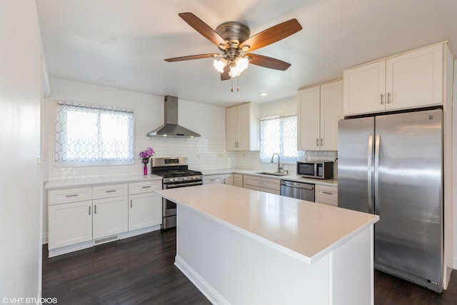 kitchen with stainless steel appliances, white cabinetry, sink, and wall chimney exhaust hood