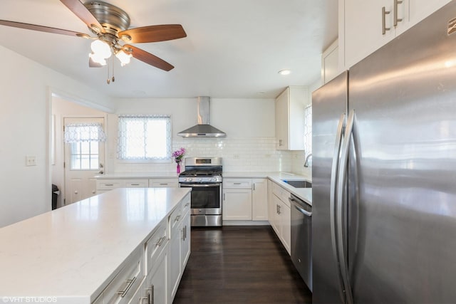 kitchen with sink, appliances with stainless steel finishes, white cabinets, decorative backsplash, and wall chimney exhaust hood