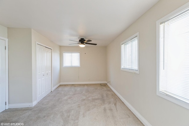 unfurnished bedroom featuring multiple windows, light colored carpet, and ceiling fan