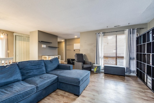 living area with a textured ceiling, visible vents, and wood finished floors