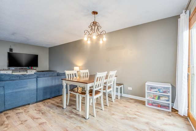 dining area featuring baseboards, an inviting chandelier, and wood finished floors