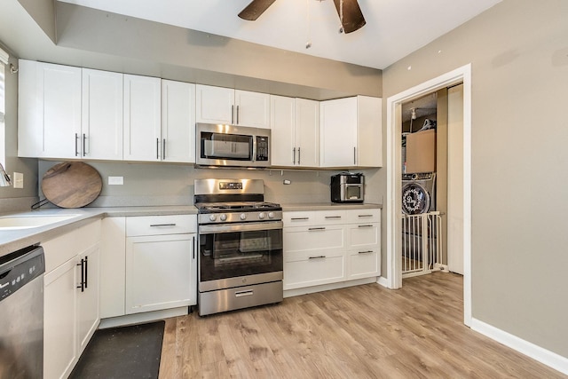 kitchen with appliances with stainless steel finishes, a sink, white cabinetry, and light wood-style floors