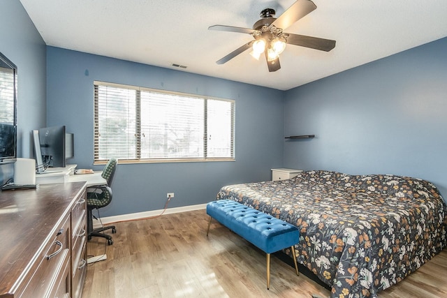 bedroom featuring ceiling fan, wood finished floors, visible vents, and baseboards