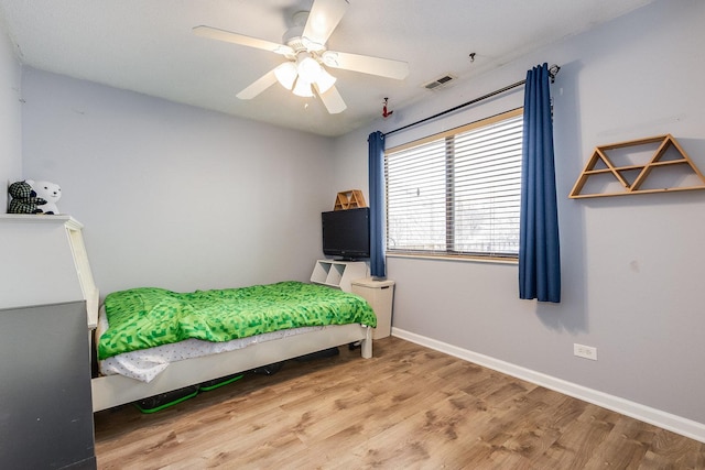 bedroom with ceiling fan, wood finished floors, visible vents, and baseboards