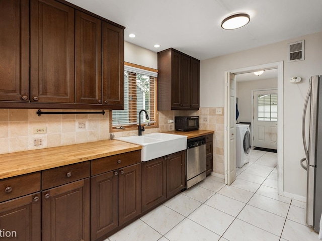 kitchen with butcher block counters, sink, washer / dryer, and stainless steel appliances