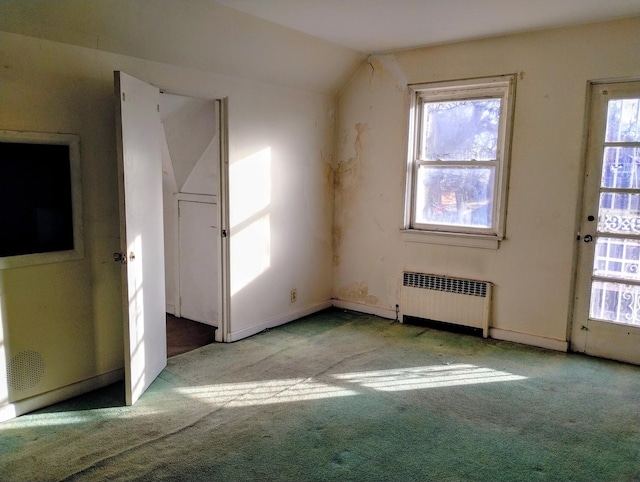 empty room featuring radiator heating unit, light colored carpet, and vaulted ceiling