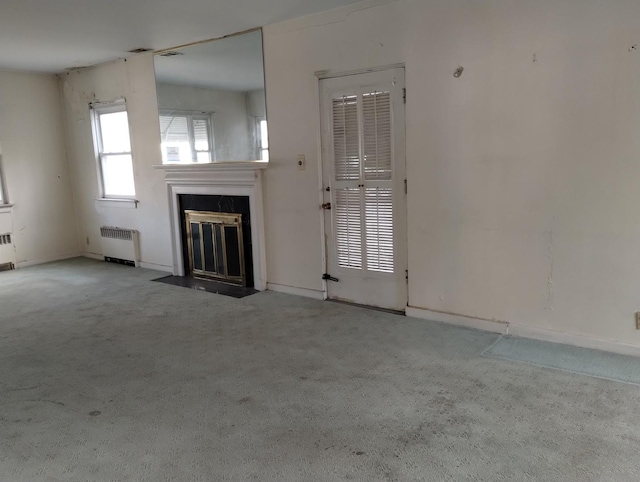 unfurnished living room featuring light carpet and radiator heating unit