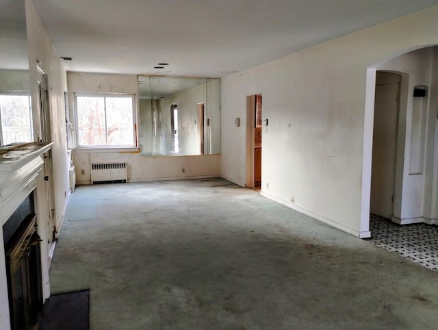 unfurnished living room featuring light colored carpet and radiator heating unit