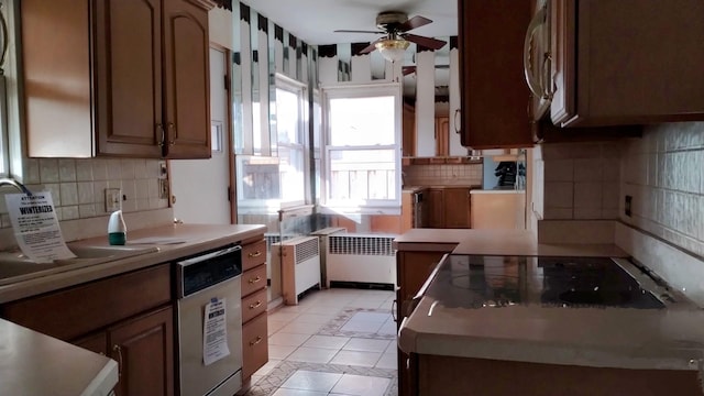 kitchen featuring radiator, dishwasher, backsplash, light tile patterned floors, and ceiling fan