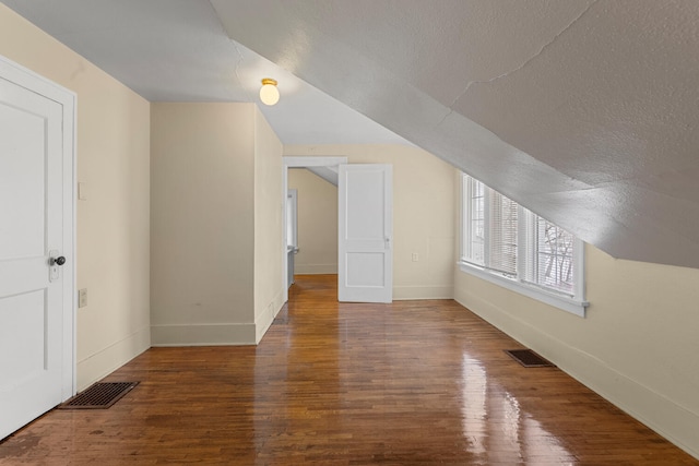 bonus room featuring vaulted ceiling, hardwood / wood-style floors, and a textured ceiling