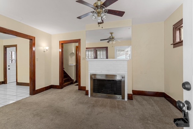 unfurnished living room with a brick fireplace, light colored carpet, and ceiling fan