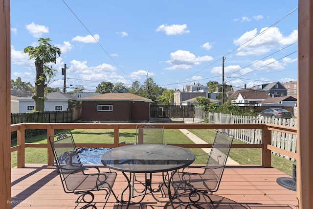 wooden deck featuring a fenced backyard, a residential view, outdoor dining area, and a yard