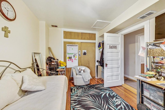 bedroom featuring wood finished floors, visible vents, and attic access