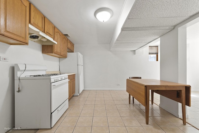 kitchen featuring white appliances, under cabinet range hood, light countertops, and light tile patterned flooring