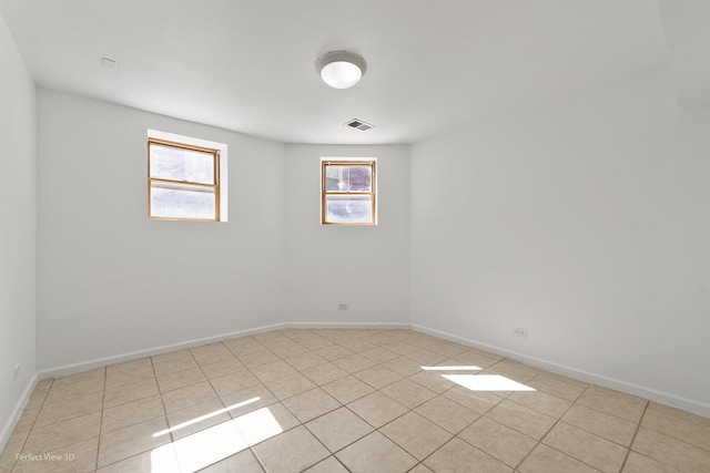 spare room featuring light tile patterned floors, visible vents, and baseboards