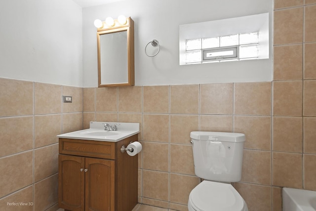 full bath featuring toilet, a wainscoted wall, tile walls, and vanity