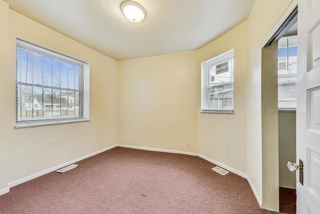 carpeted spare room featuring baseboards and visible vents