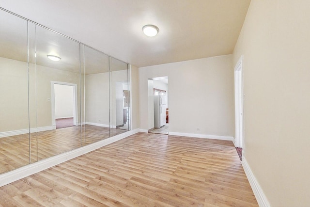 unfurnished room with light wood-type flooring and baseboards