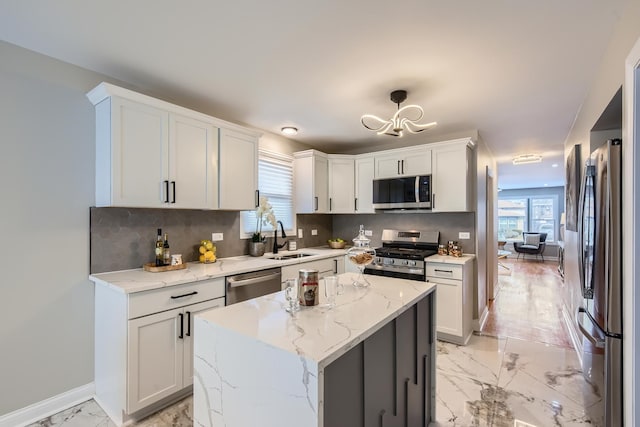 kitchen featuring sink, white cabinetry, stainless steel appliances, a center island, and light stone counters