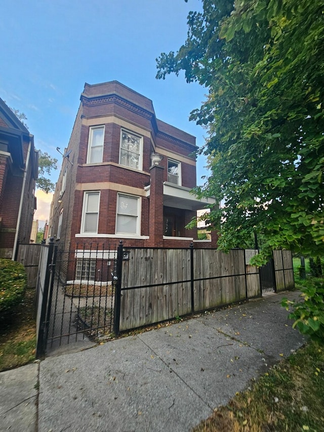 view of front of home with brick siding, a fenced front yard, and a gate