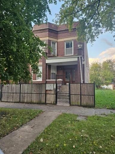 view of front of property with brick siding, a fenced front yard, and a gate