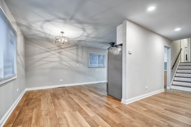 interior space featuring ceiling fan with notable chandelier and light hardwood / wood-style floors