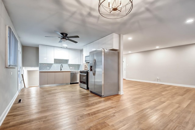 kitchen featuring white cabinetry, hanging light fixtures, stainless steel appliances, and light wood-type flooring