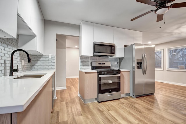 kitchen with stainless steel appliances, tasteful backsplash, sink, and white cabinetry