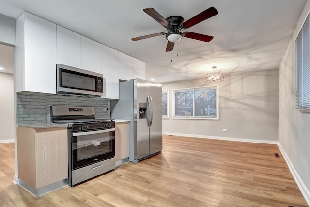 kitchen featuring tasteful backsplash, white cabinetry, ceiling fan, stainless steel appliances, and light wood-type flooring