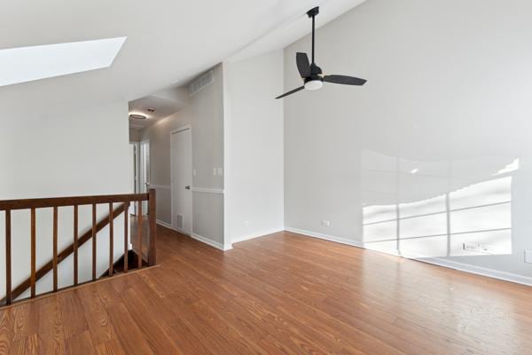 unfurnished room with wood-type flooring, lofted ceiling with skylight, and ceiling fan