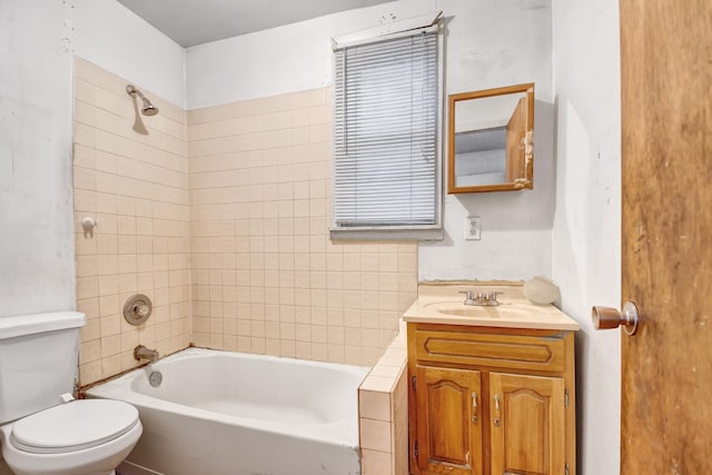 full bathroom featuring vanity, tiled shower / bath, and toilet