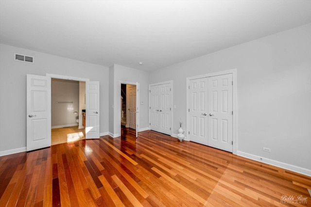 unfurnished bedroom with multiple closets and light hardwood / wood-style floors